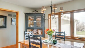 A dining area with a wooden table, chairs, a chandelier, and a cabinet with glass doors. - Tennis Court & Deck: Pet-friendly Charles City Gem (Charles City)