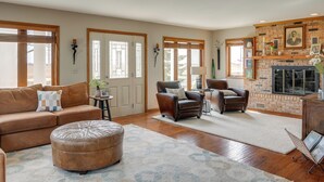 A spacious living room with a brown leather sofa, two armchairs, a wooden coffee table, and a fireplace. - Tennis Court & Deck: Pet-friendly Charles City Gem (Charles City)