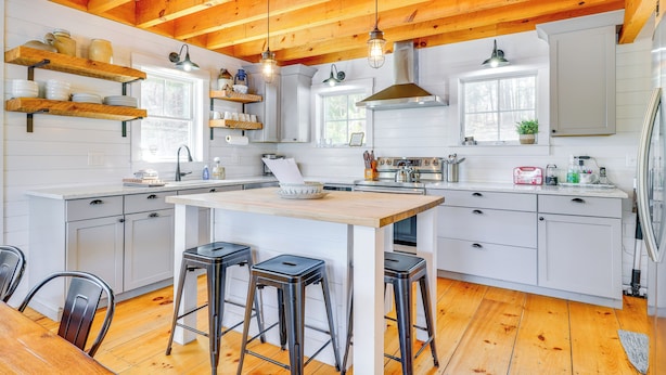 A modern kitchen with wooden beams, white cabinetry, and a central island with stools. - Paddle, Swim & Hike: Family Lake House in Vermont (Wallingford)