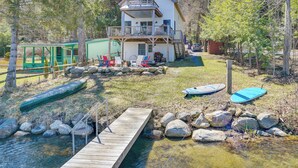 A two-story house with a balcony, a dock, and a small boat. - Paddle, Swim & Hike: Family Lake House in Vermont (Wallingford)