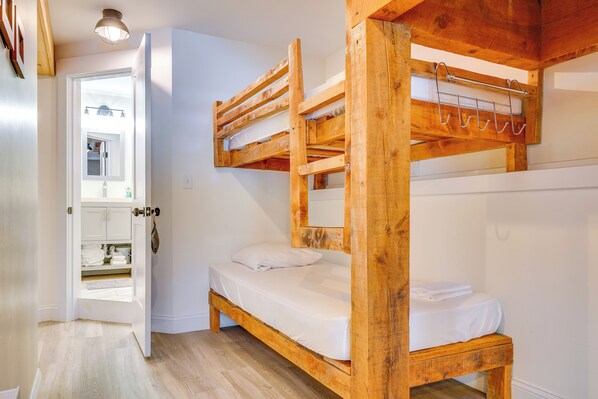A bunk bed room with a wooden ceiling and a door leading to a bathroom.