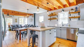 A modern kitchen with wooden beams, a central island, and white cabinetry. - Paddle, Swim & Hike: Family Lake House in Vermont (Wallingford)