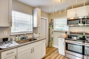 A modern kitchen with white cabinets, a stainless steel oven, and a granite countertop.