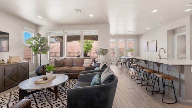 A spacious living room with a large sofa, a coffee table, and a dining area with bar stools. - Desert Serenity: Community Pool + Hot Tub, Ping Pong Table! (Washington)