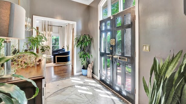 A modern interior with a large black door, a chandelier, and various plants. - The Royale 2B 4B Luxury Garden Pool Yoga Room (Tampa)