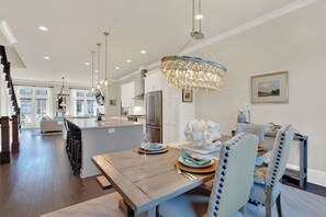 A spacious kitchen with a central island, stainless steel appliances, pendant lighting, and a chandelier.