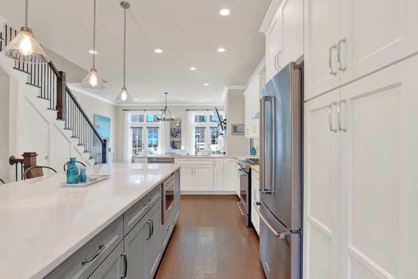 A modern kitchen with white cabinets, stainless steel appliances, and pendant lighting.