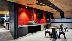 A modern kitchen with a red backsplash, a ceiling fan, and a seating area with chairs.