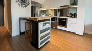 A modern kitchen with white cabinetry, a central island, stainless steel appliances, and a decorative wall piece.