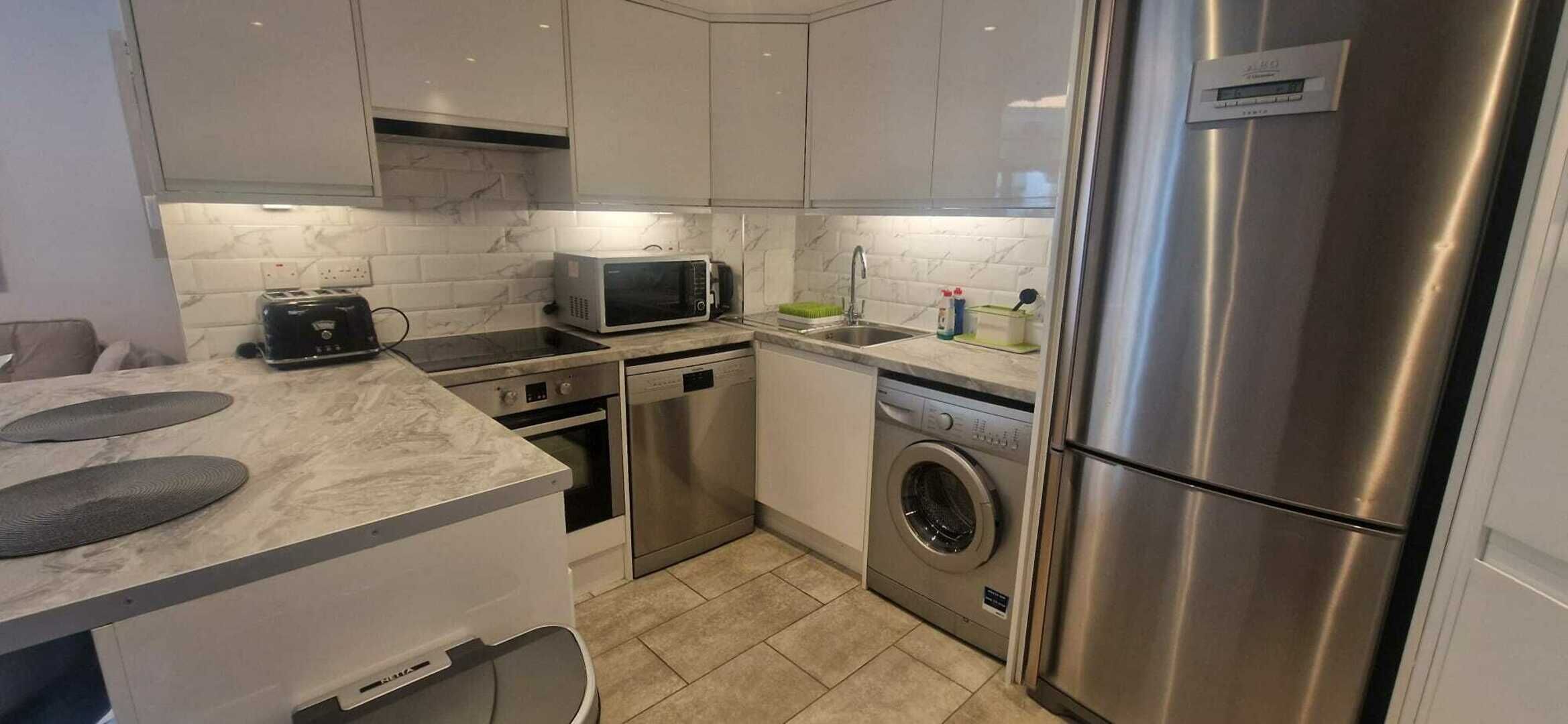 A modern kitchen with stainless steel appliances, a built-in oven, microwave, and dishwasher.