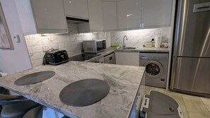 A modern kitchen with a built-in toaster, microwave, dishwasher, and stainless steel refrigerator.