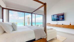 Una camera da letto moderna con un letto grande, una TV e vista sull'oceano.