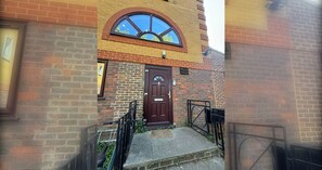 A brick building with a brown door, a small window, and a CCTV sign. - Bright Canal-Side Flat, Canada Water (Greater London)