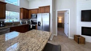 Una cocina moderna con encimeras de granito, electrodomésticos de acero inoxidable y armarios de madera.