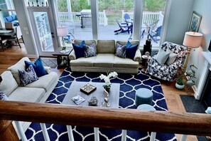 Un salon comprenant un canapé, des fauteuils, une table basse et un tapis à motifs.