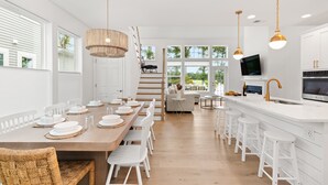 Une cuisine moderne avec des meubles blancs, une table à manger en bois et des tabourets de bar.