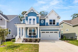 A two-story house with a front porch, a garage, and a small front yard.