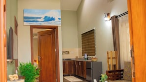 A modern living room with a wooden coffee table, a sofa, and a kitchen area with wooden cabinets and a refrigerator.