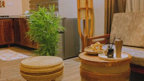 A cozy living room with a wooden coffee table, a round ottoman, a potted plant, and a sofa.