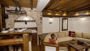A rustic interior with a stone archway, wooden furniture, and a cozy seating area.