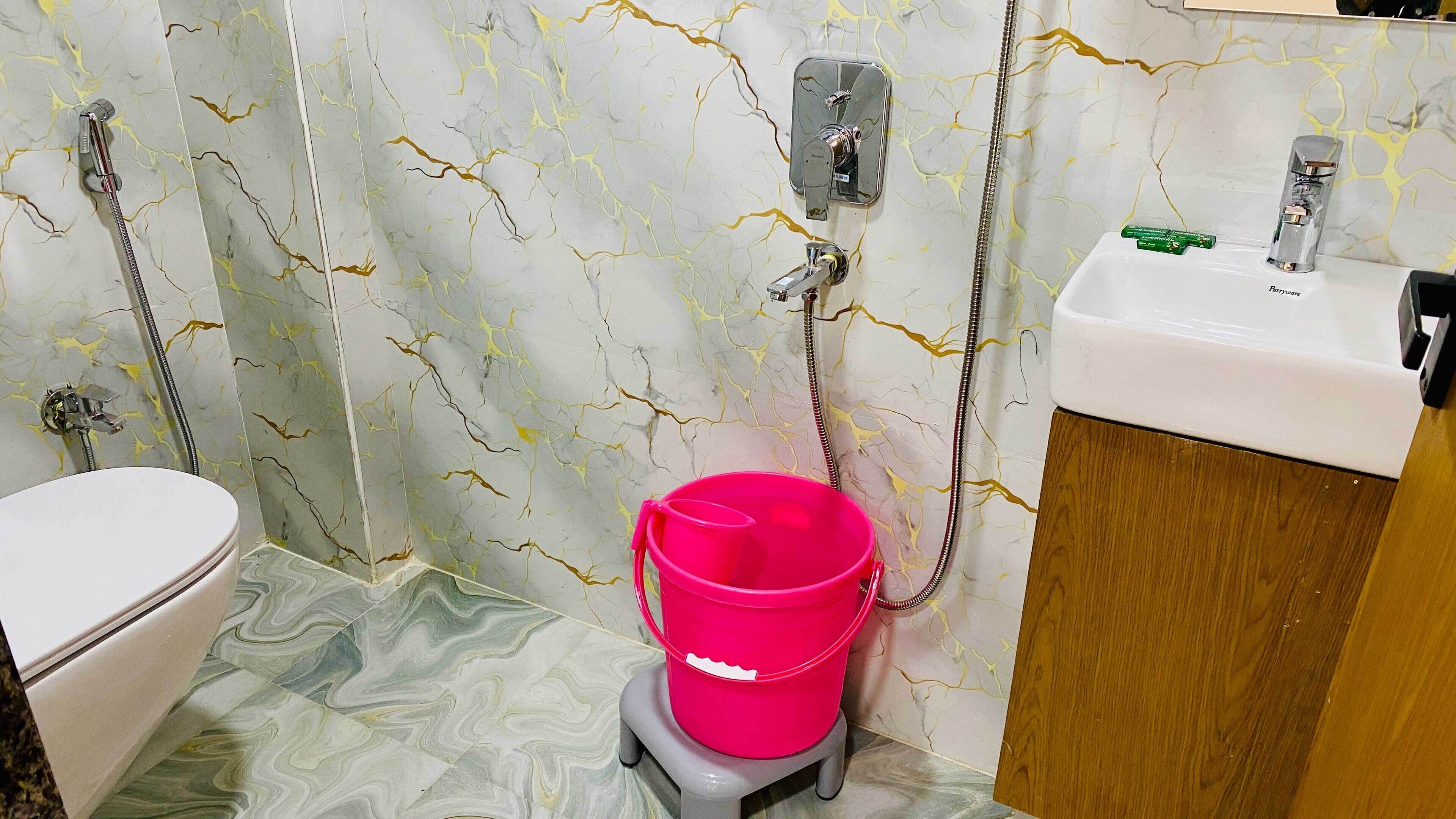 A bathroom with a toilet, a sink, and a shower with a hose.