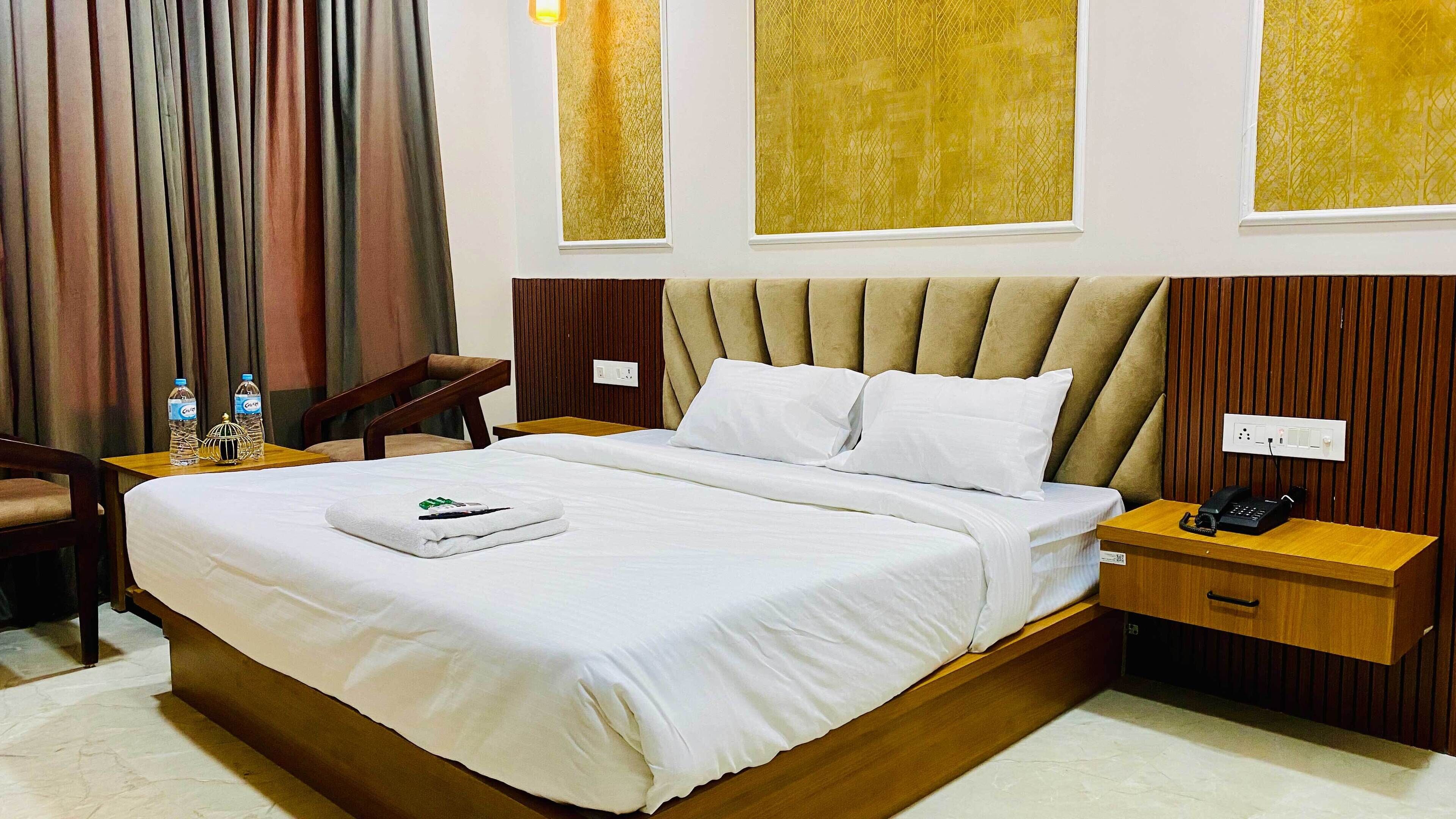Une chambre d’hôtel avec un grand lit, deux tables de chevet, une chaise et un bureau avec un téléphone.