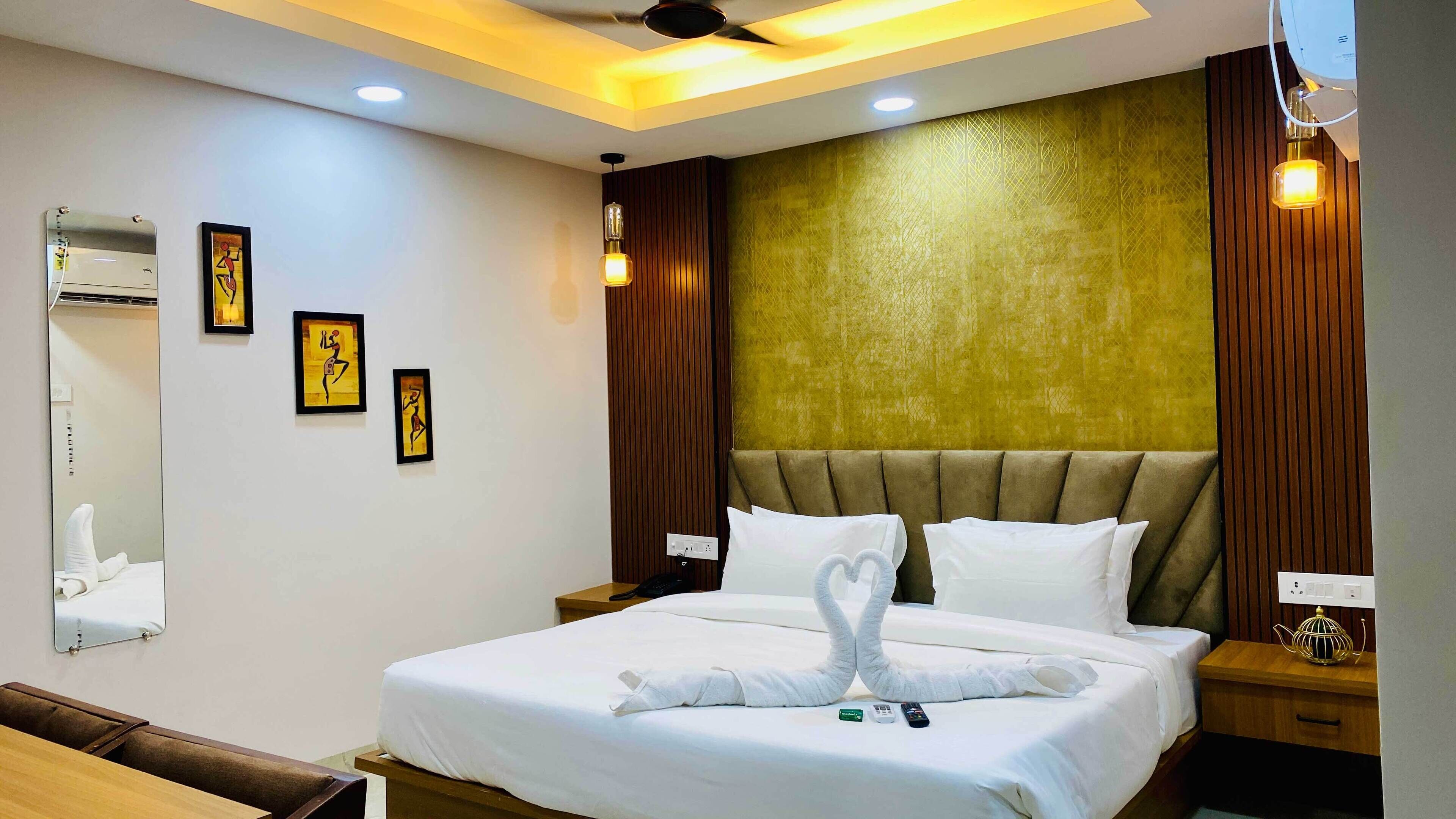 Habitación de hotel con cama, mesita de noche, espejo y cuadros en la pared.