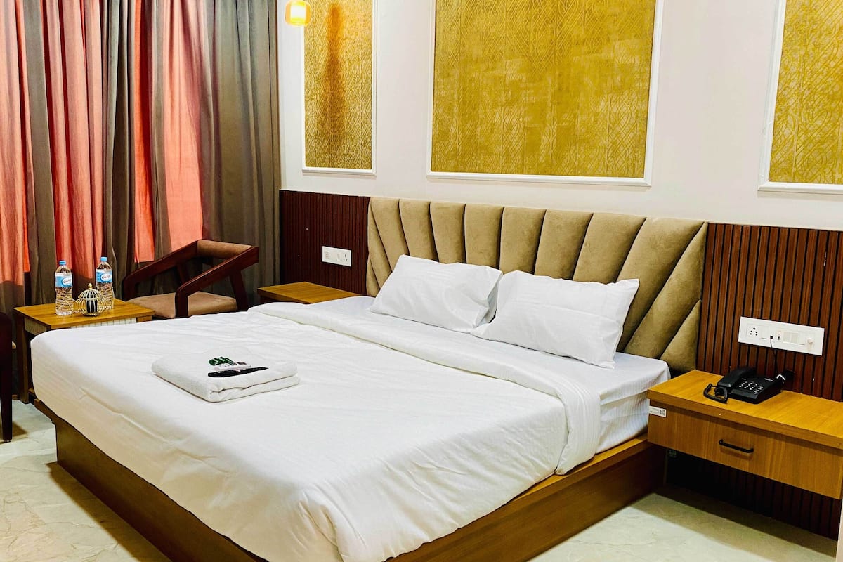 A hotel room with a bed, a desk, a chair, and curtains.
