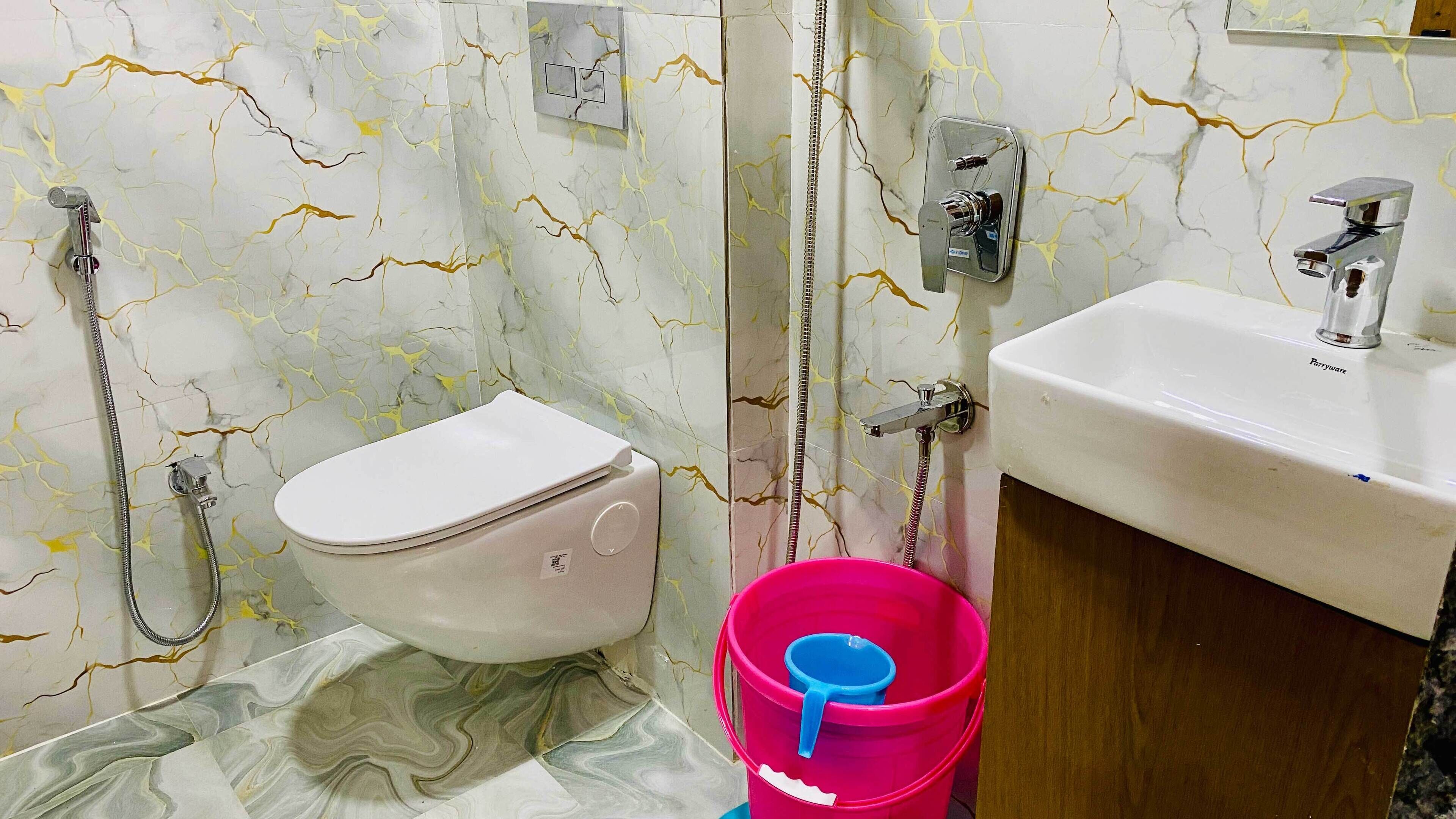 A bathroom with a toilet, shower, and sink.