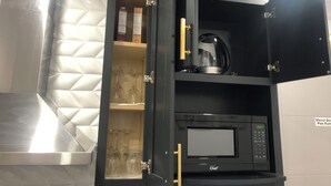 A kitchen with a black microwave and a coffee maker on the countertop.
