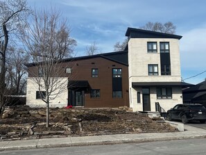 A modern two-story house with a visible address number, a driveway, and a parked car.