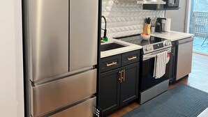A modern kitchen with dark cabinetry, stainless steel appliances, and a tiled backsplash.