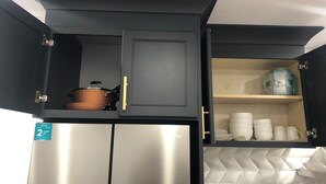 A kitchen with dark cabinets, a stainless steel refrigerator, and a herringbone-patterned backsplash.