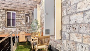 Un petit espace extérieur aménagé avec une table et des chaises, entouré de murs en pierre et d’un bâtiment en briques.