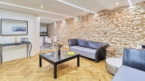 Un salon moderne avec un mur en pierre, un canapé, une table basse et un coin repas visible au fond.