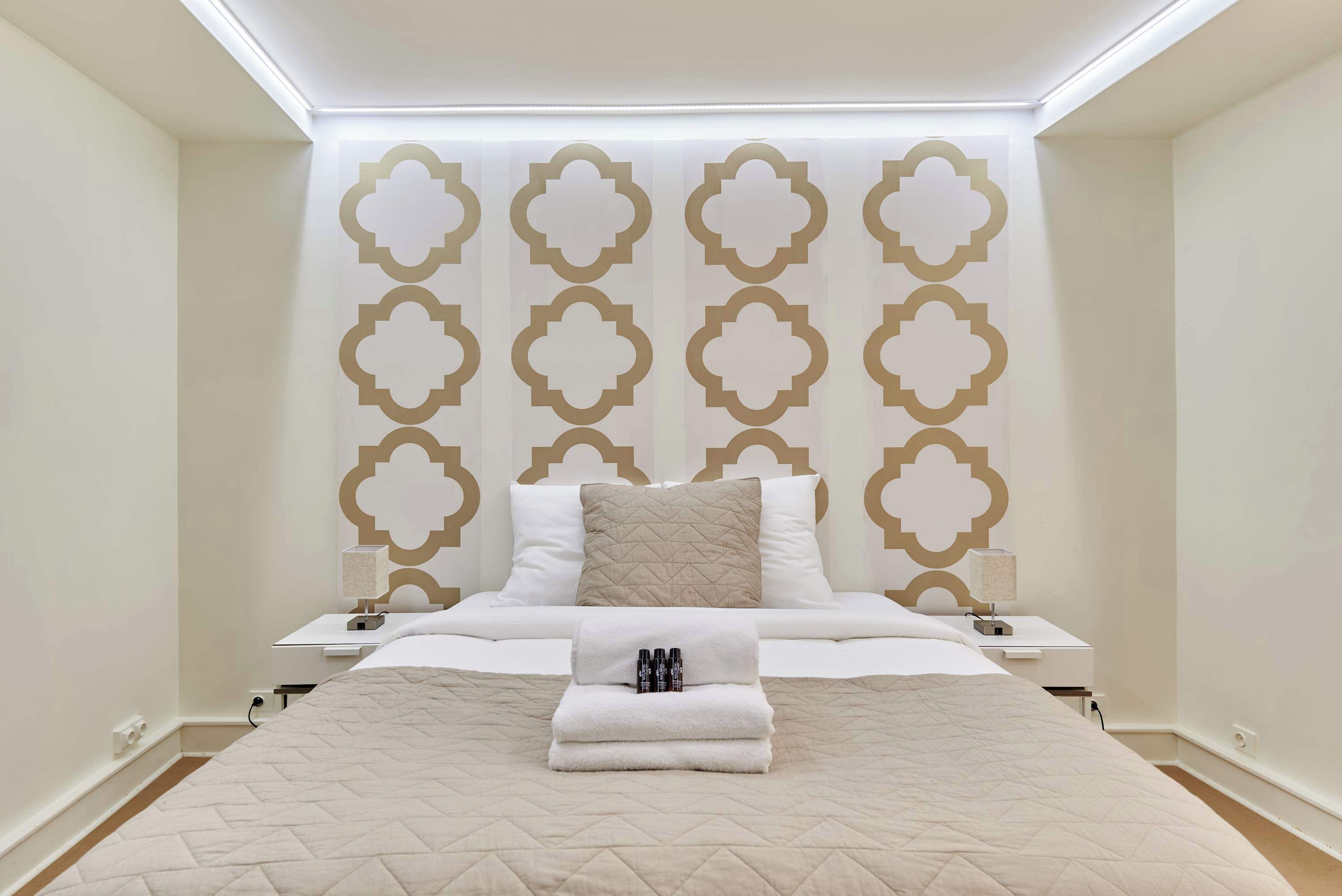 Une chambre d’hôtel bien aménagée, avec un grand lit, une table de chevet avec une lampe et un panneau décoratif au mur.