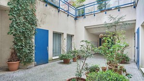 A courtyard with potted plants, a blue door, and a blue railing.