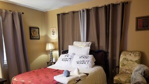 A hotel room with a bed, a chair, a lamp, and curtains.