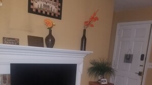 A living room with a fireplace, a television, and a small table with a welcome sign.
