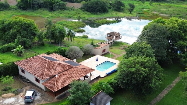 Une maison avec un toit en tuiles, une piscine et un petit quai donnant sur un étang.