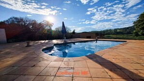 Une piscine à bord incurvé, entourée d’une terrasse carrelée.