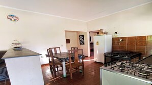 Une cuisine de taille réduite équipée d’une cuisinière à gaz, d’un réfrigérateur et d’une table à manger avec des chaises.
