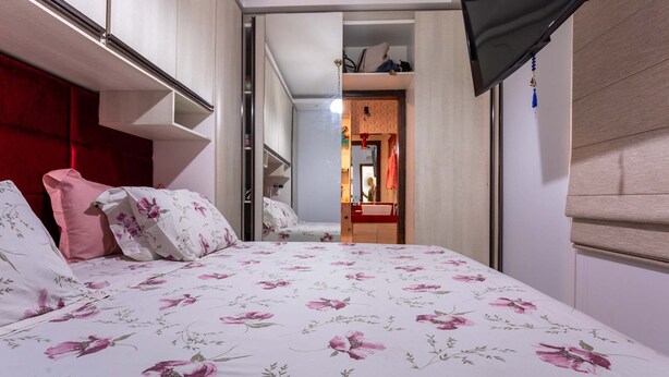 Un dormitorio con cama, armario y baño visible a través de una puerta abierta.