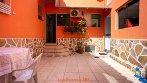 Un patio al aire libre con una mesa, sillas, una planta en maceta y una escalera que conduce a la entrada.
