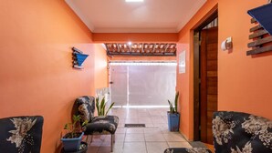 Un pasillo con paredes anaranjadas, una puerta de madera y dos sillones tapizados con motivos florales.