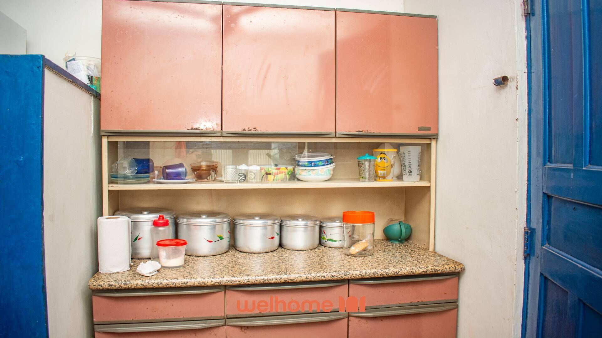 A kitchen with pink cabinets, a granite countertop, and various kitchen items.