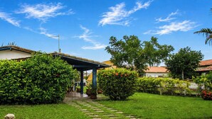 Una casa con porche cubierto, un jardín con sendero de piedra y un cielo azul despejado.