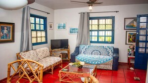 Una sala de estar con un sofá, televisor y una mesa con un florero.