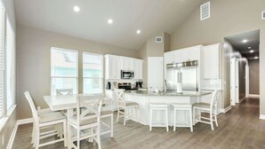 A modern kitchen with white cabinetry, a central island with seating, and built-in appliances.