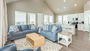 A spacious living area with two sofas, a coffee table, and a kitchen in the background.